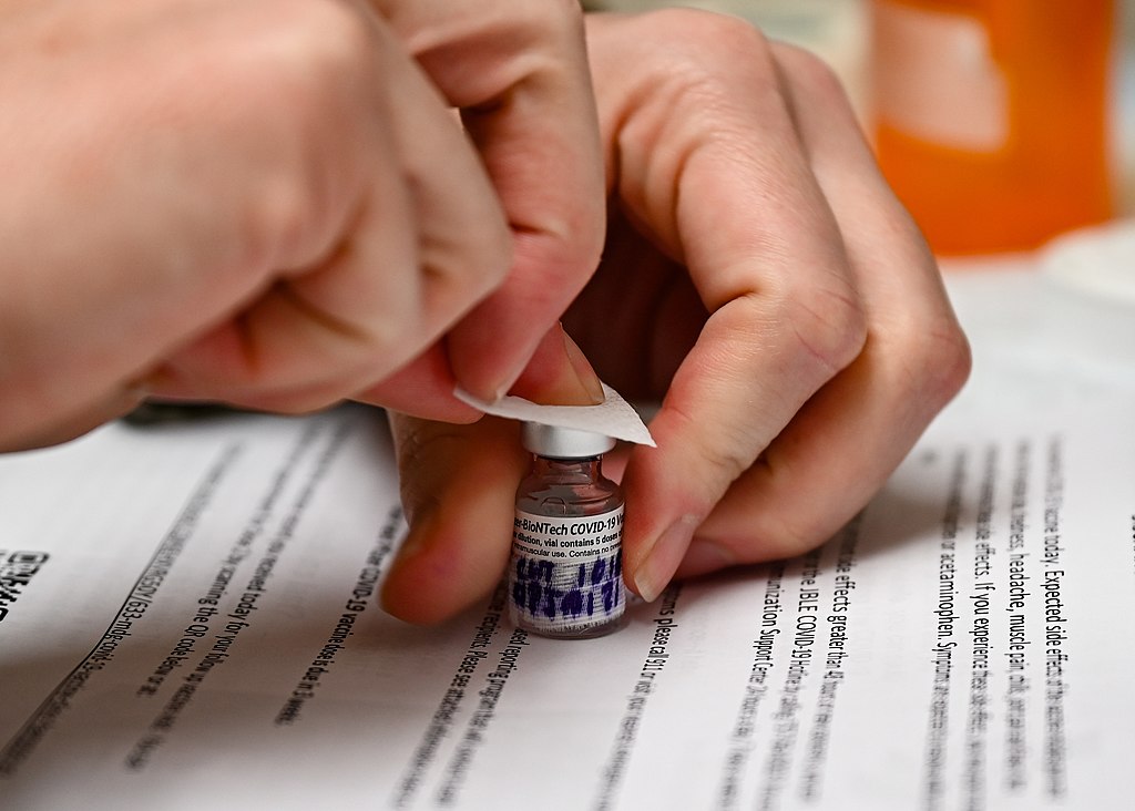 close up picture of a covid-19 vaccine vial being opened