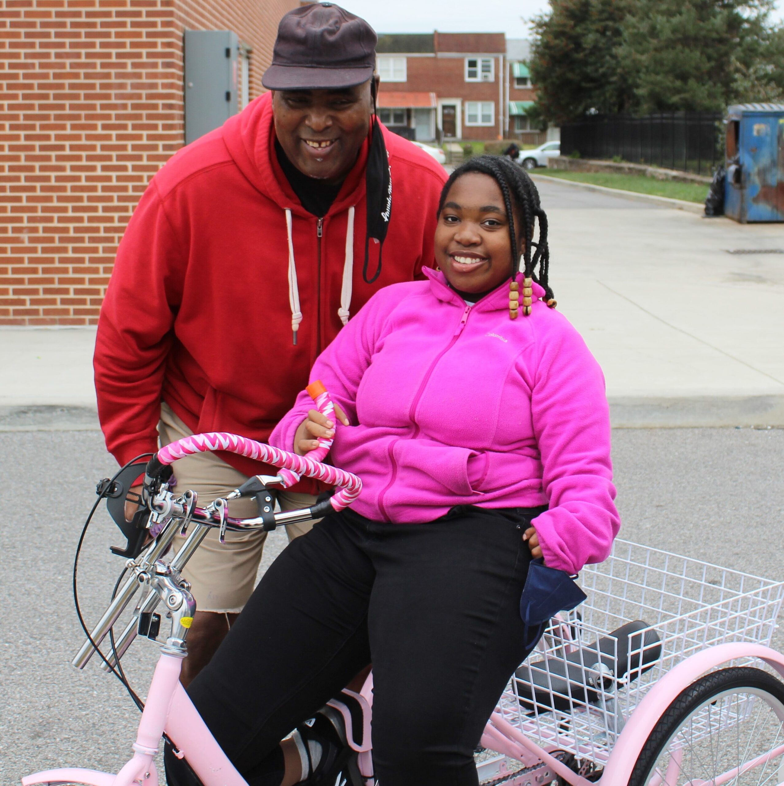 Teen on her new pink trike with customized features with dad by her side.