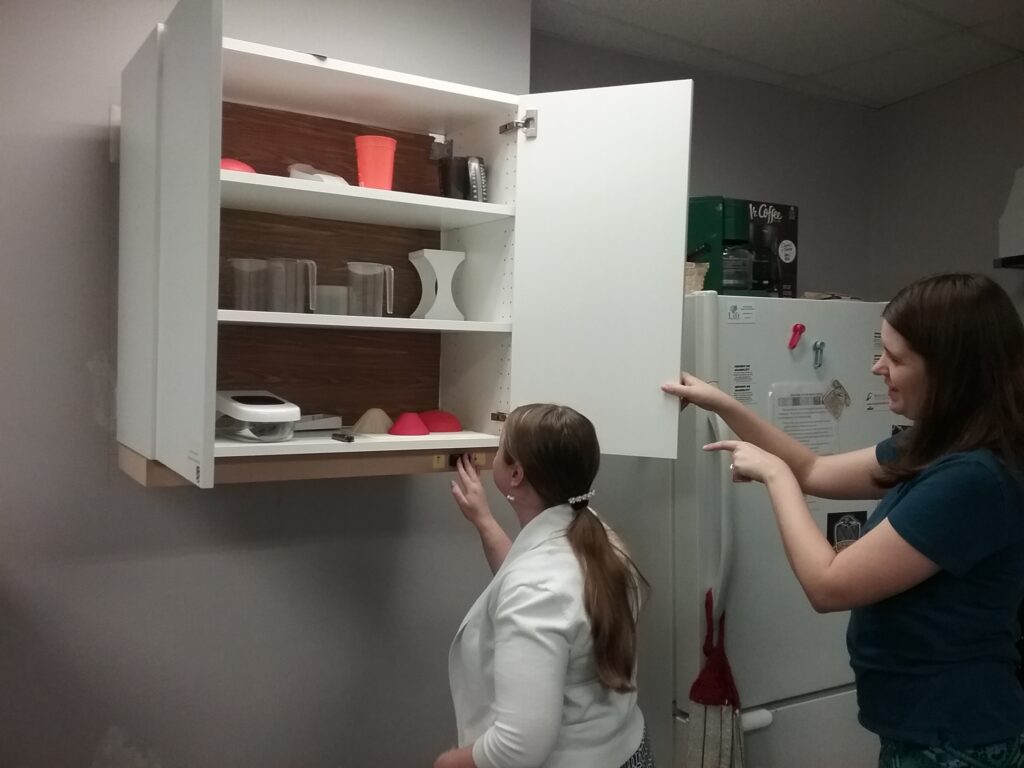 Two women at a kitchen cabinet that has been updated for accessibility for the blind.