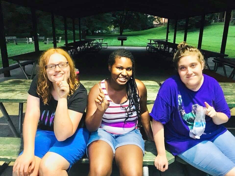 Three teens sitting together smiling on a bench during a Connect program session.