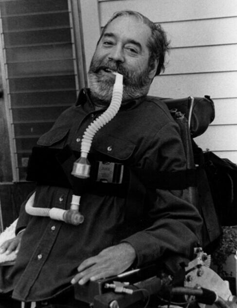 Black and white photo of Ed Roberts in a motorized wheelchair with a breathing tube.