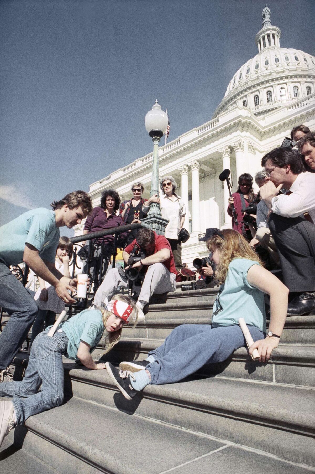 A group of people with disabilities pull themselves up the steps of the United States Capitol Building.
